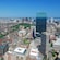 An expansive city view encompassing buildings, streets, trees, bodies of water, boats and sky